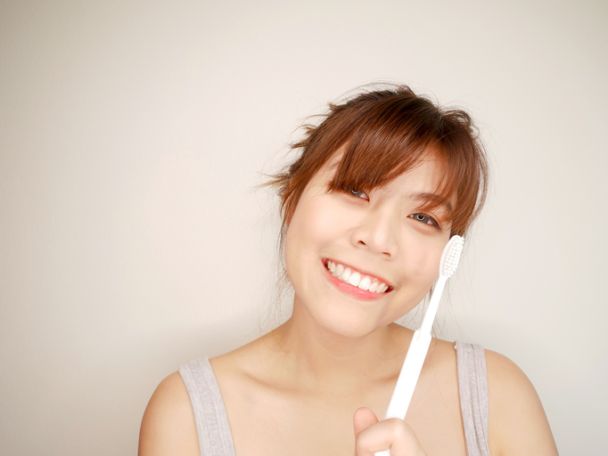 Lady smiling widely while holding on a toothbrush